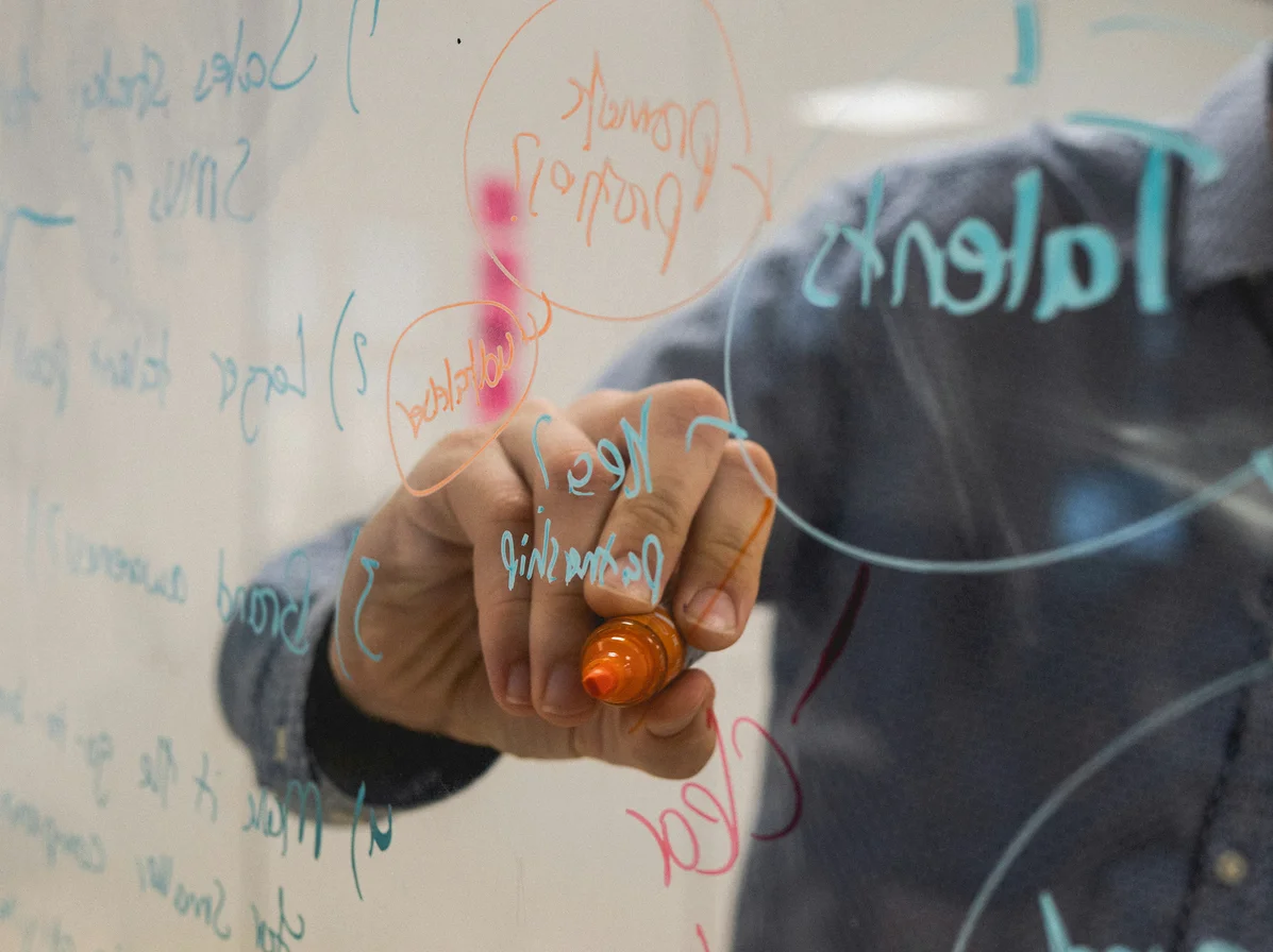 A person brainstorming marketing strategies on a whiteboard A person brainstorming marketing strategies on a whiteboard